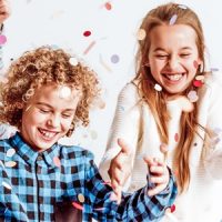 Zwei Kinder werfen mit Konfetti